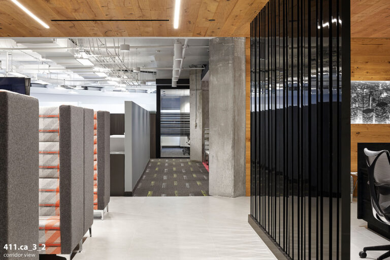 Office corridor with a sleek, black textured wall, with couches with red and gray.
