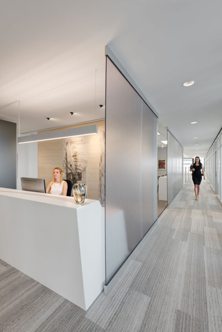 Modern office with gray flooring, and large white marble reception desk.
