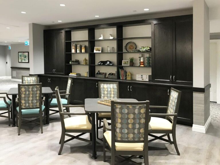 Dining area for retirement home with black built in bookshelves.
