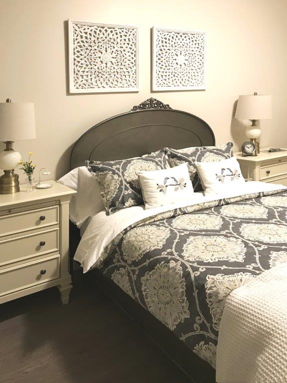 Cozy Bedroom with made up bed with a gray headboard.