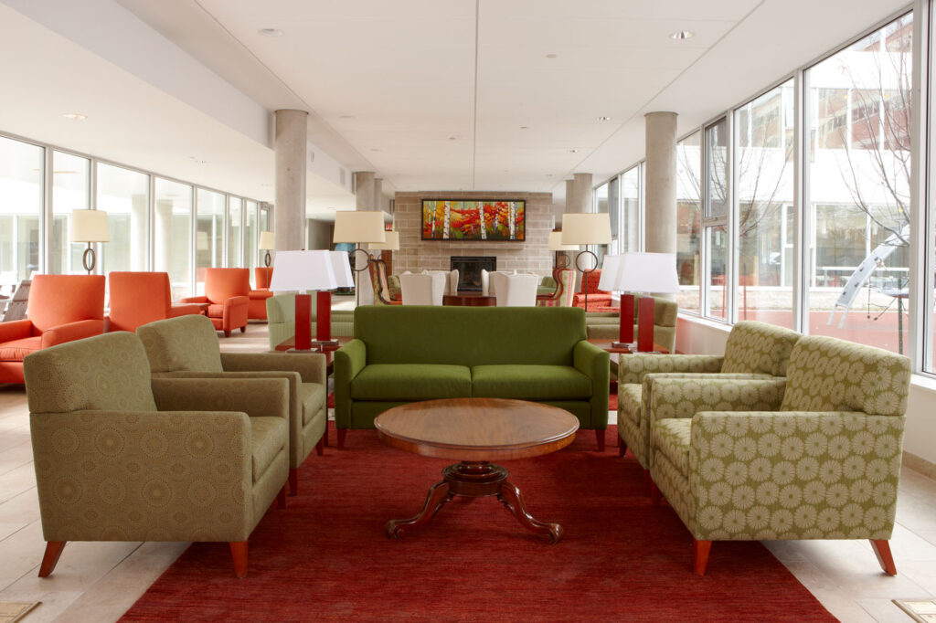 Common living room space at Ronald McDonald House with red rug and green seating.