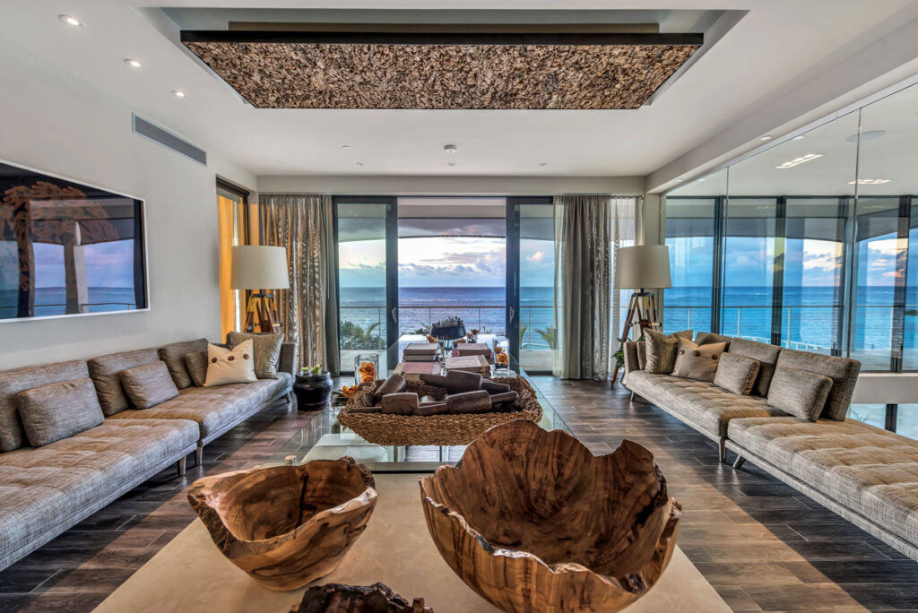 Serene lounge space with upholstered bench seating, and a view to the sea.