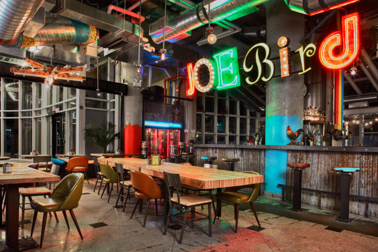 Dining and bar area of Joe Bird restaurant, with corrugated metal covering the bar and fixed stool seating.