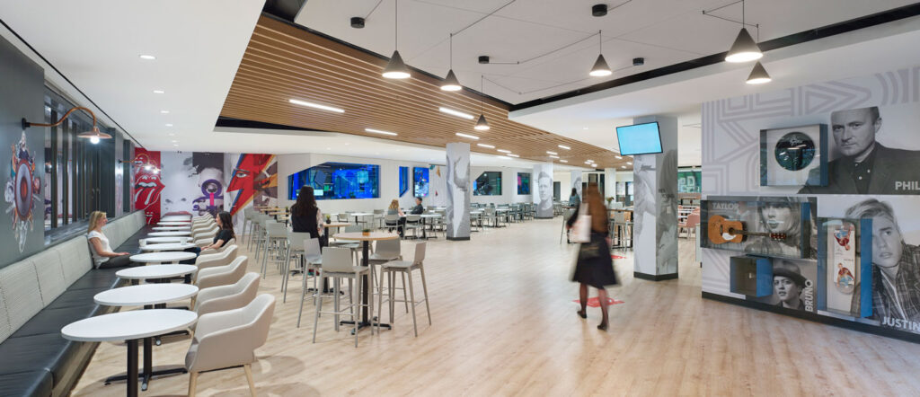 Open employee cafeteria space with pale wood floors and a accent wall with company history.