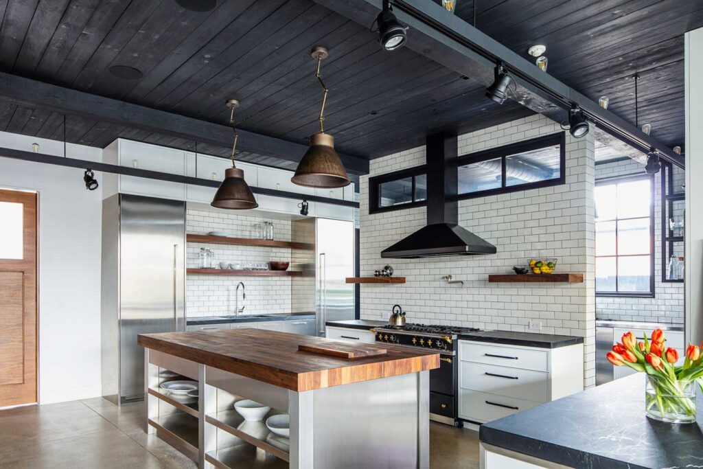 Chefs kitchen with large butcher block island and walls lined in white subway tile.