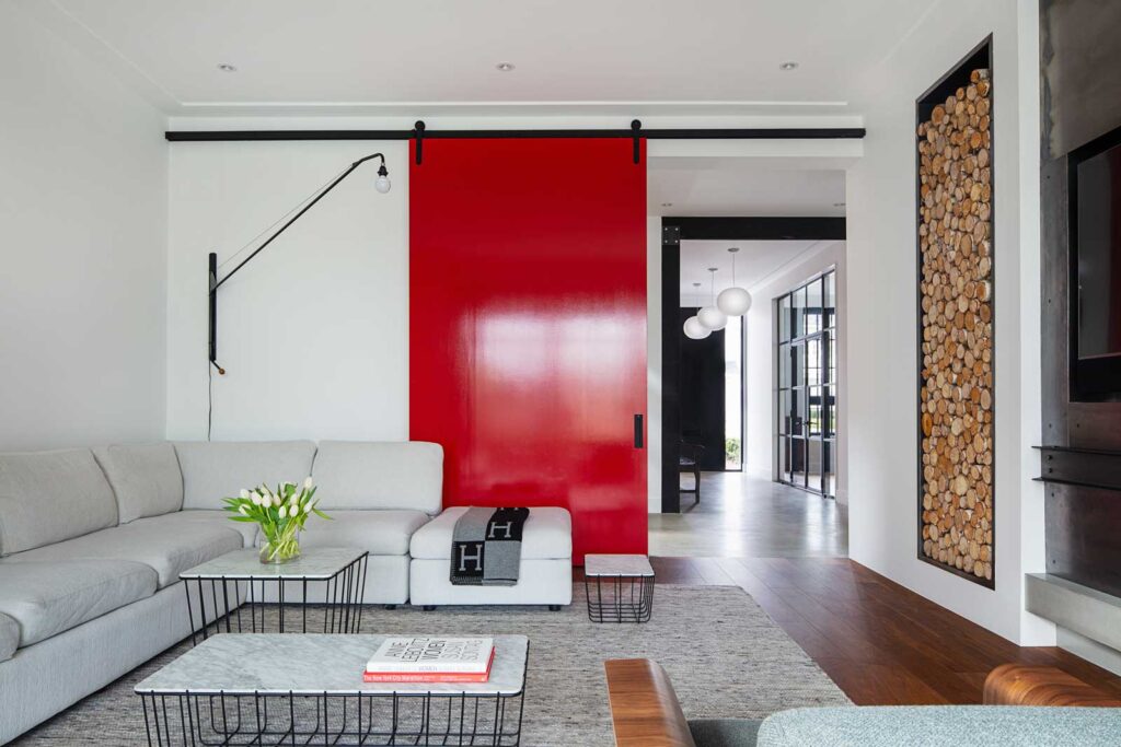 Family room with wood floors, large white sectional and eye-catching red sliding door.