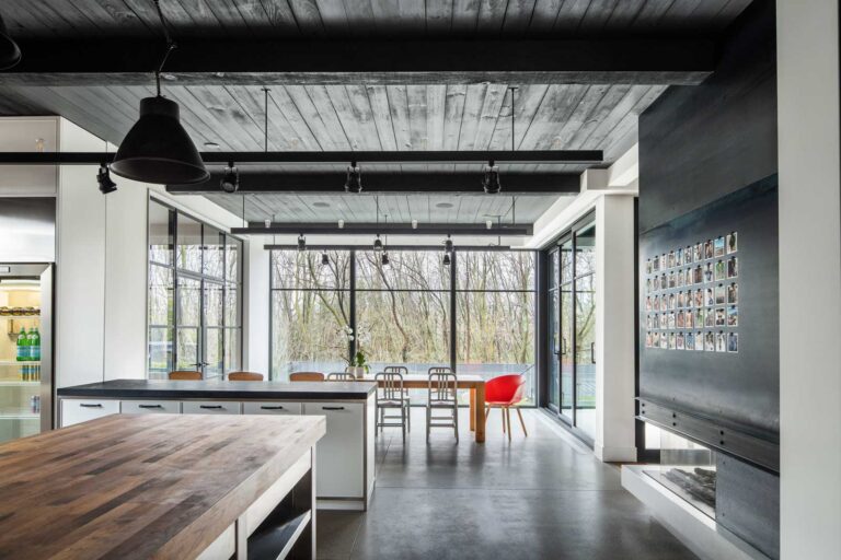 Kitchen and dining room with dark, poured concrete floors and a wood ceiling.