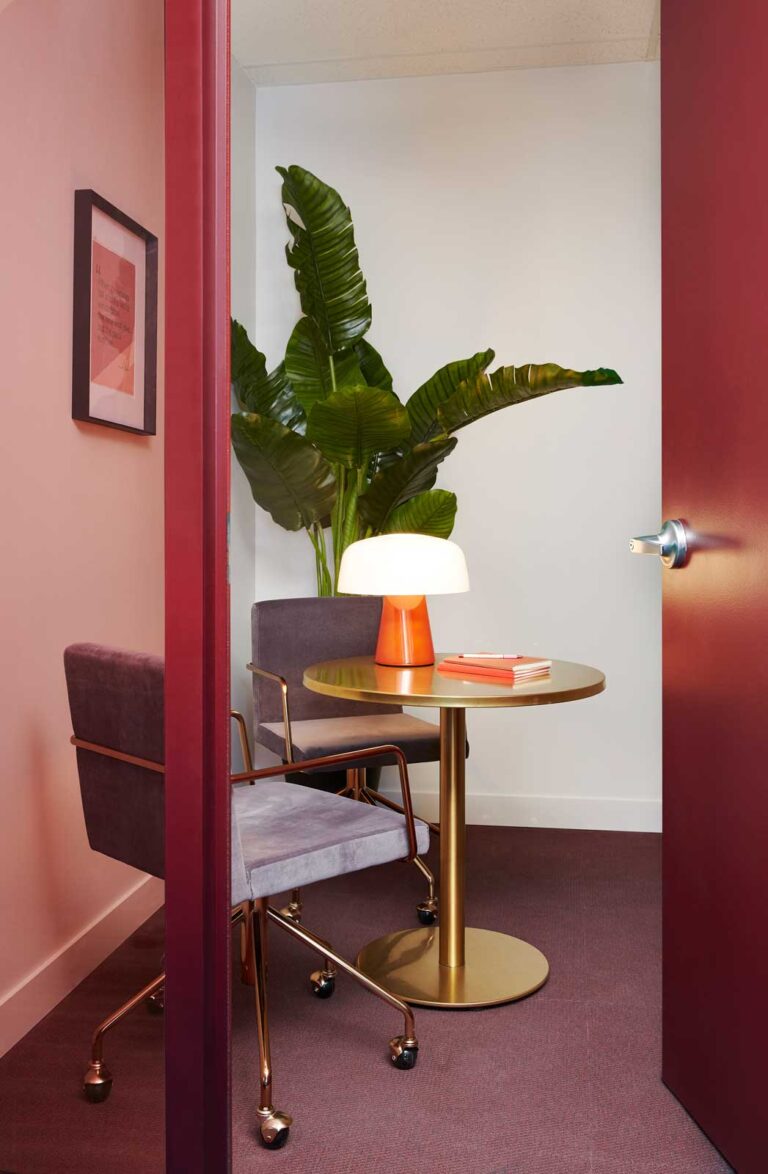 A meeting room with deep red trim, decorative lamp and two office chairs with brass hardware.