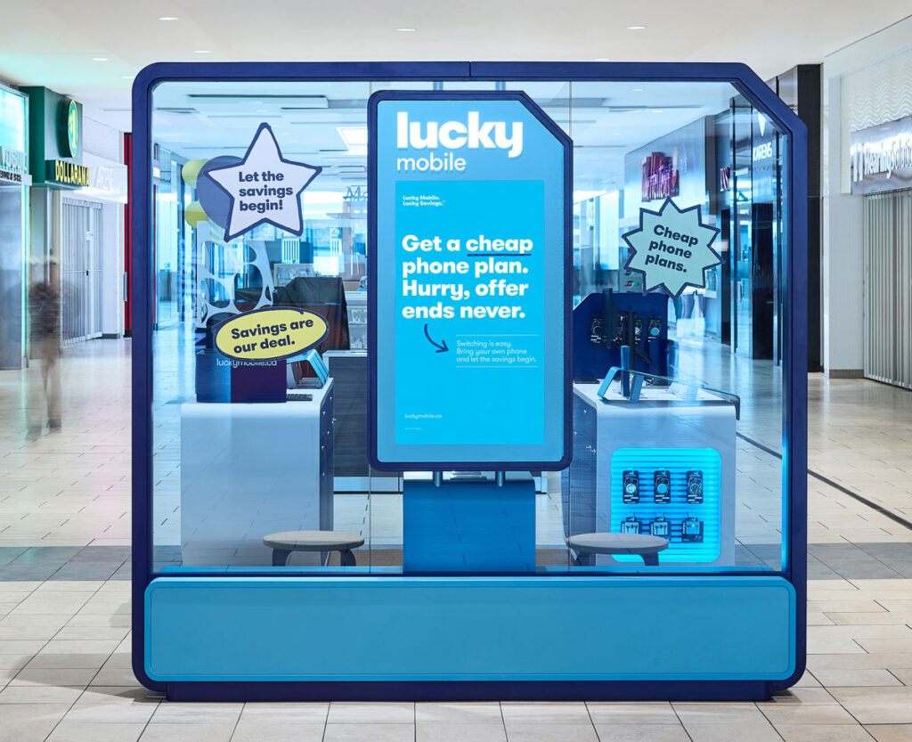 Lucky Mobile kiosk in the shape of a SIM card with transparent brand blue plexiglass demarcating space.