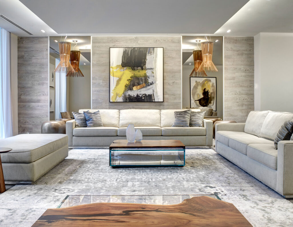 Large seating area in this condo lobby with pale gray couches, gray wood panelled walls and abstract black and yellow art.