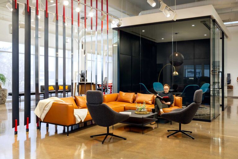 An orange couch with black armchairs becomes a cool place to meet against a wooden slat installation.
