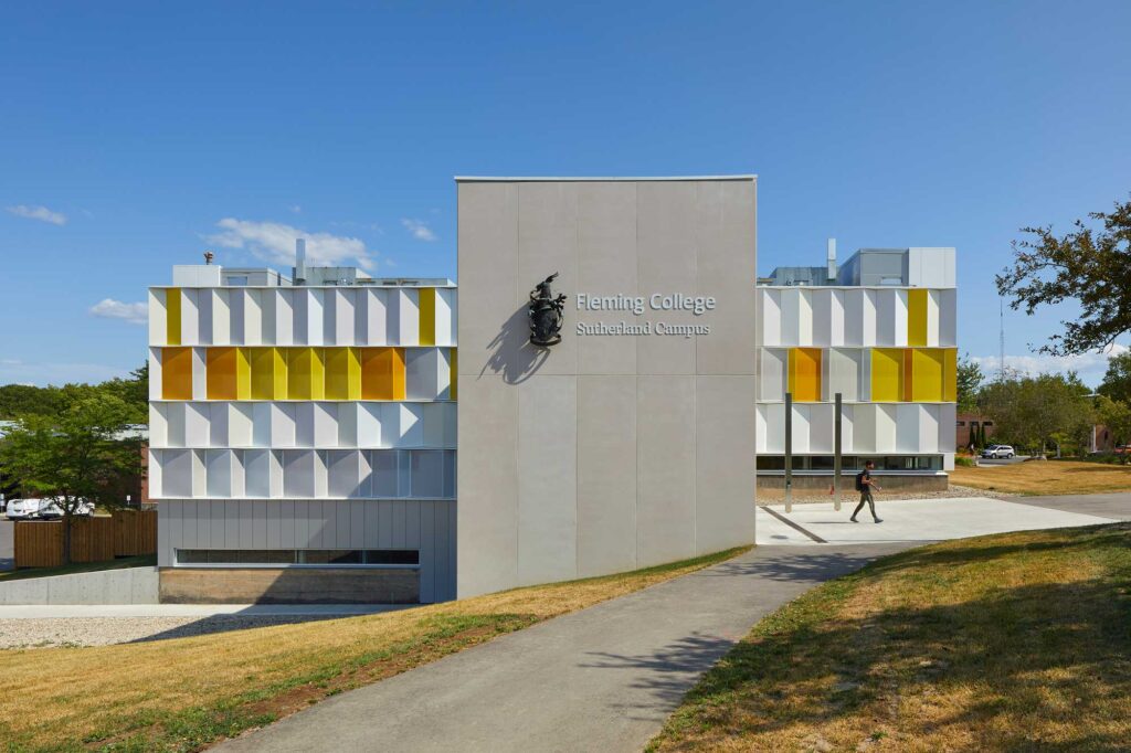 Exterior view of Fleming College with two newly clad wings on either site of the original concrete facade emblazoned with the college's crest.