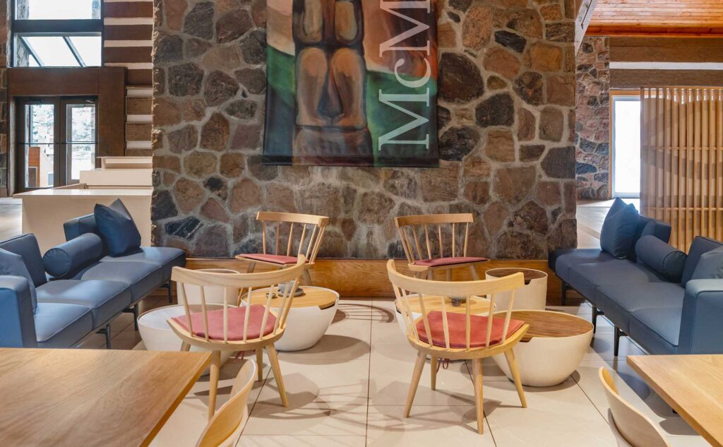 Wooden chairs are placed opposite blue sofas in the cafe of the McMichael Canadian Art Collection.