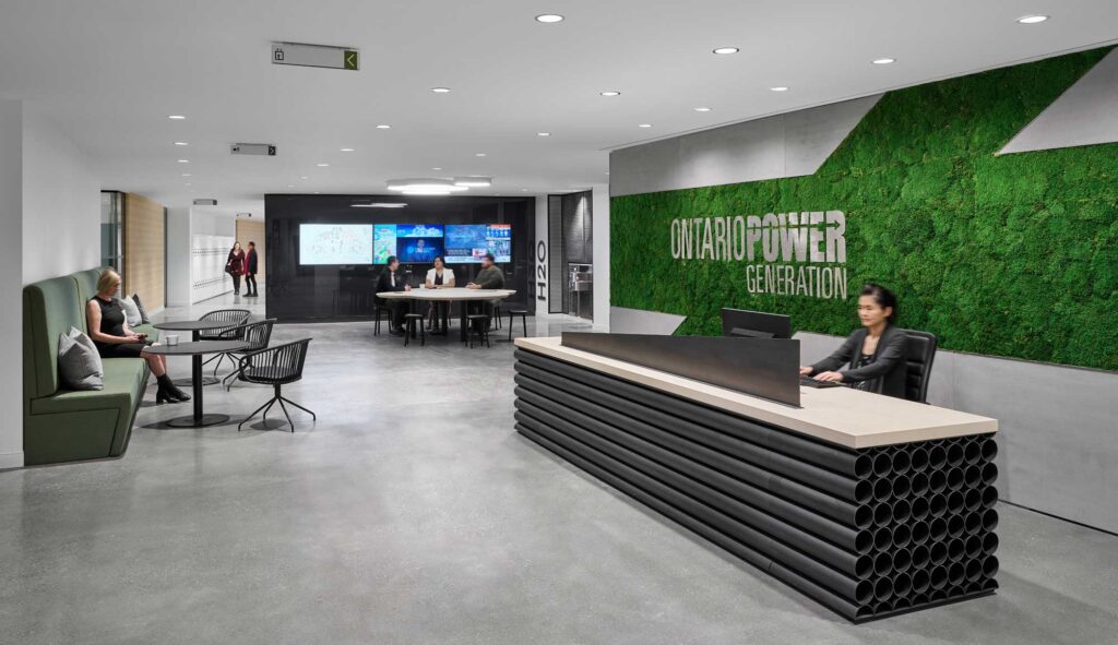 The reception desk at Ontario Power Generation's new office is made of calendria cooling tubes with a green carpeted brand wall in behind.