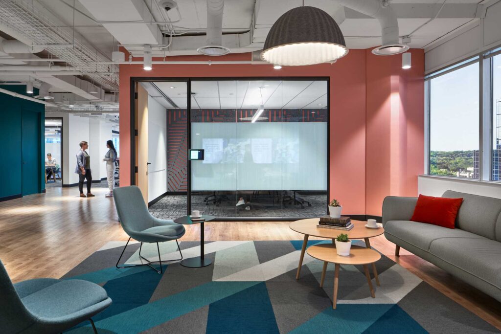 A casual meeting space at Uber's Toronto office has two chairs with low round tables and a long sofa.