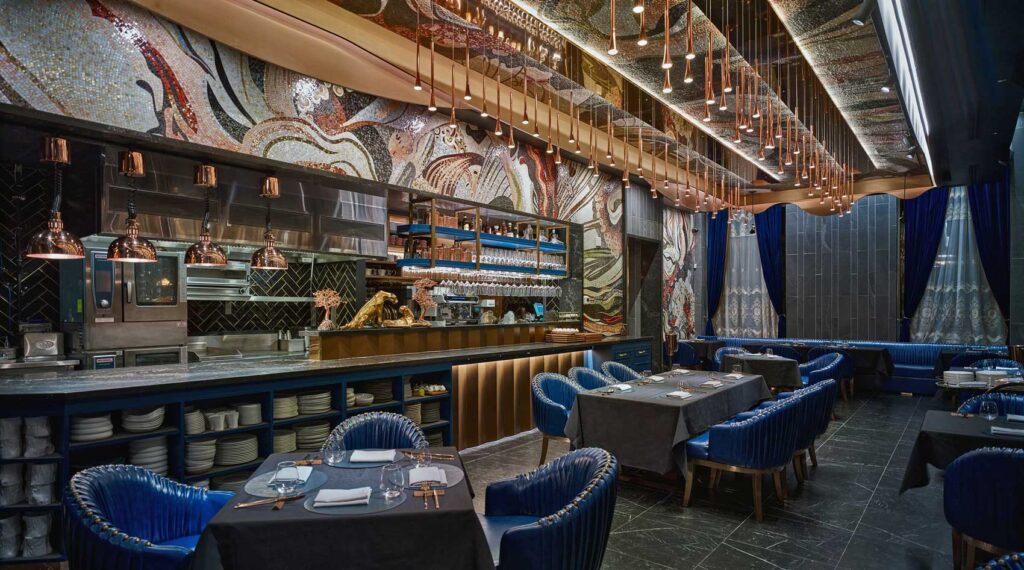 Wide view of a restaurant space with a flowing mosaic overhead with copper coloured pendant lights.