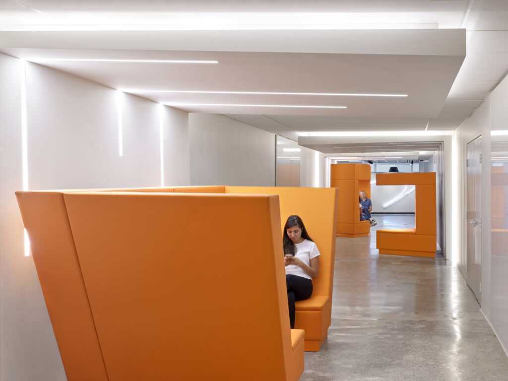 Modern colorful orange sitting booths for lounging or working, found along the long white corridors.