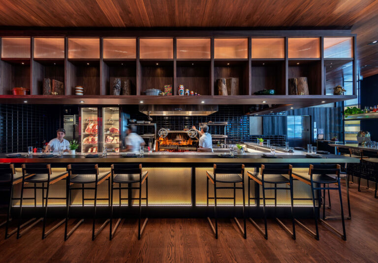Chefs work in the open kitchen surrounded by a high bar.