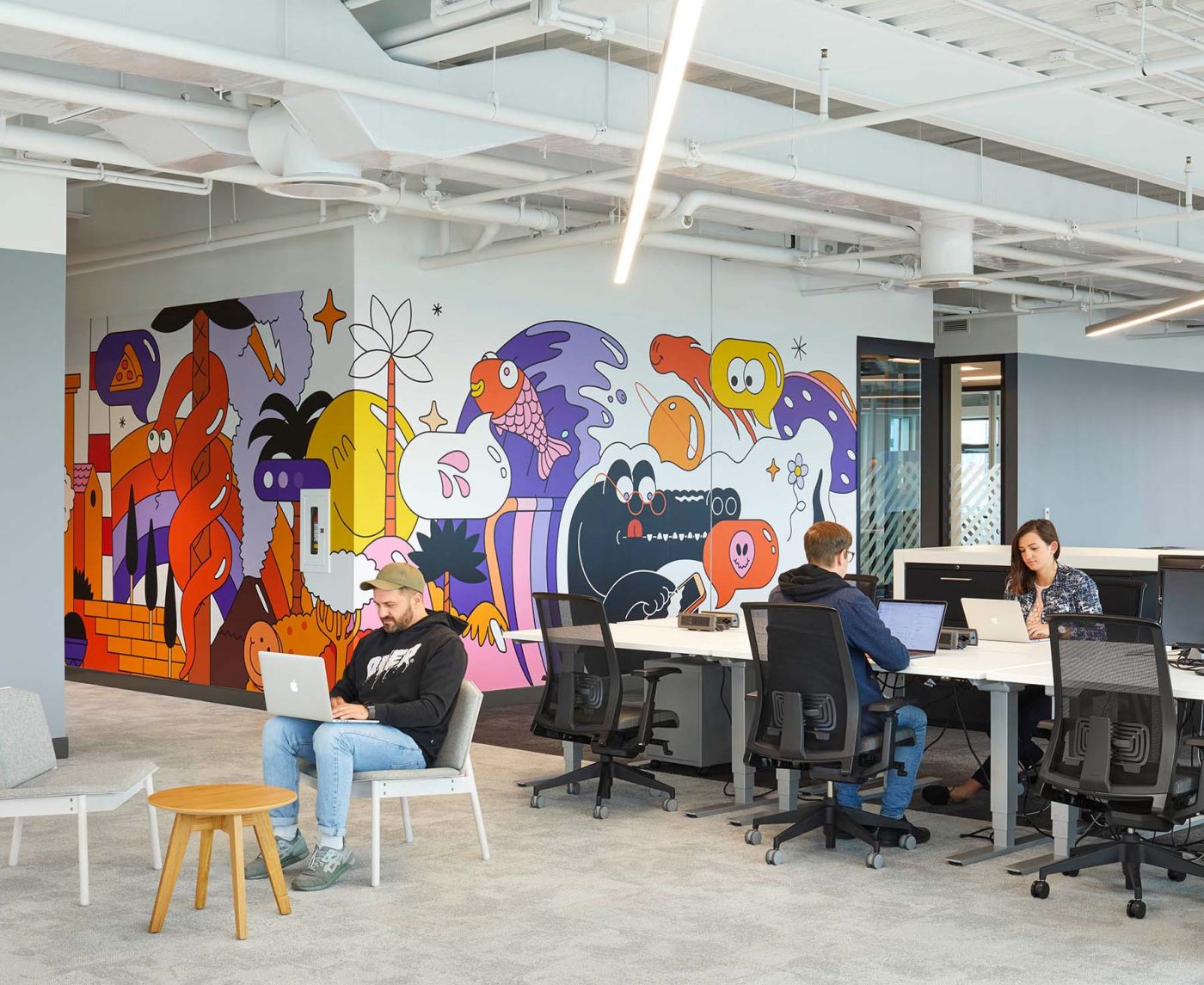 A colourful cartoon wall graphic lights up the office space and provides some levity in the focused heads down space.