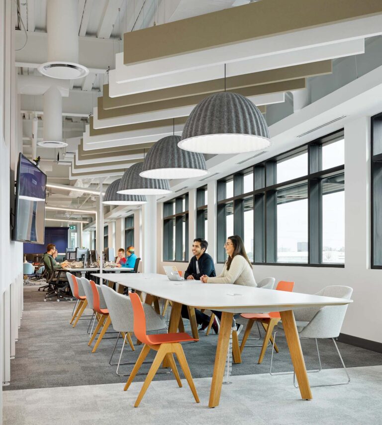 Long tables at the Text Now office against a wall of windows provide workspace and meeting space for employees.