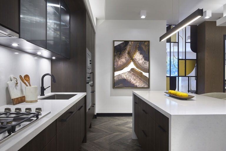 Kitchen vignette-Modern Dark colored wood kitchen cabinets and island with white countertops and walls with beautiful abstract artwork on the wall.