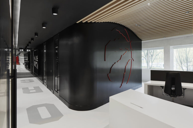 Black feature wall with a discrete 3D Raptors logo outlined in red