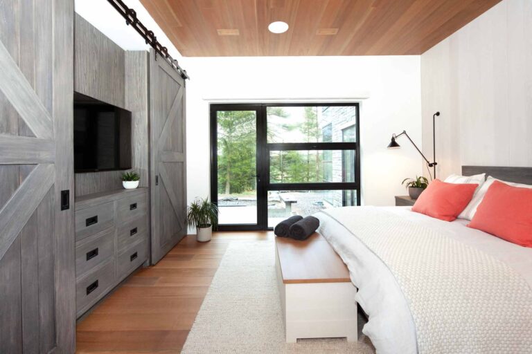 Beautifully serene guest room showing custom barn door cabinetry to hide TVs and provide storage