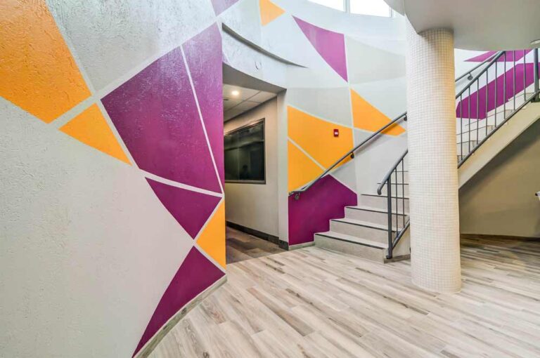 Colorful feature wall in the ground level circulation area with a geometric design in deep purple and oranges