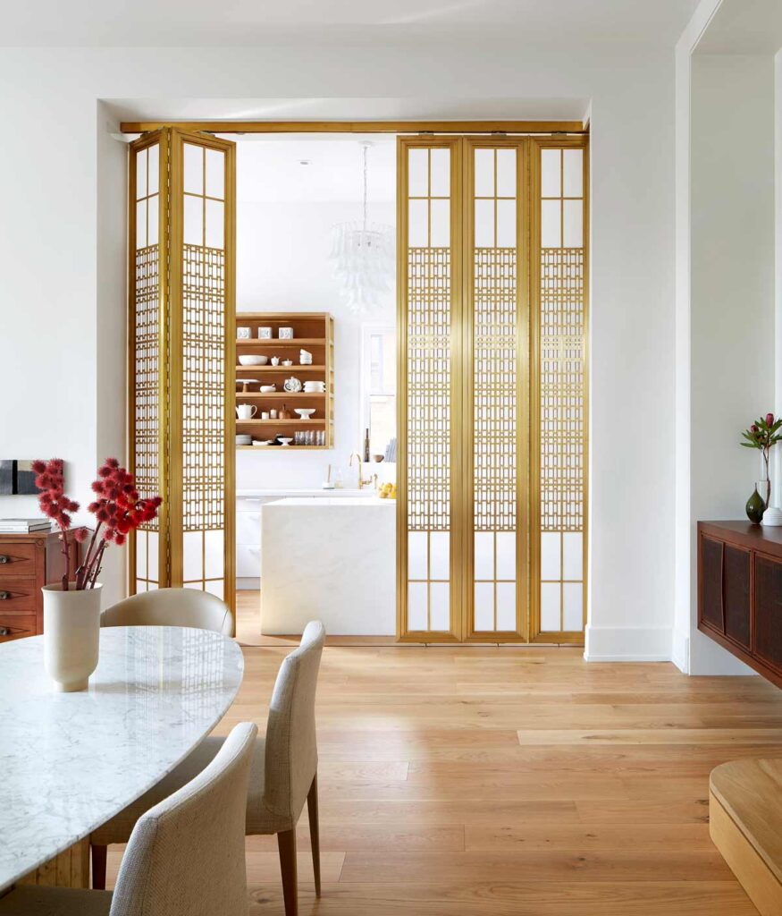 The 1930's inspired brass screen is half open, showing the intricate pattern detail, with kitchen peeking through