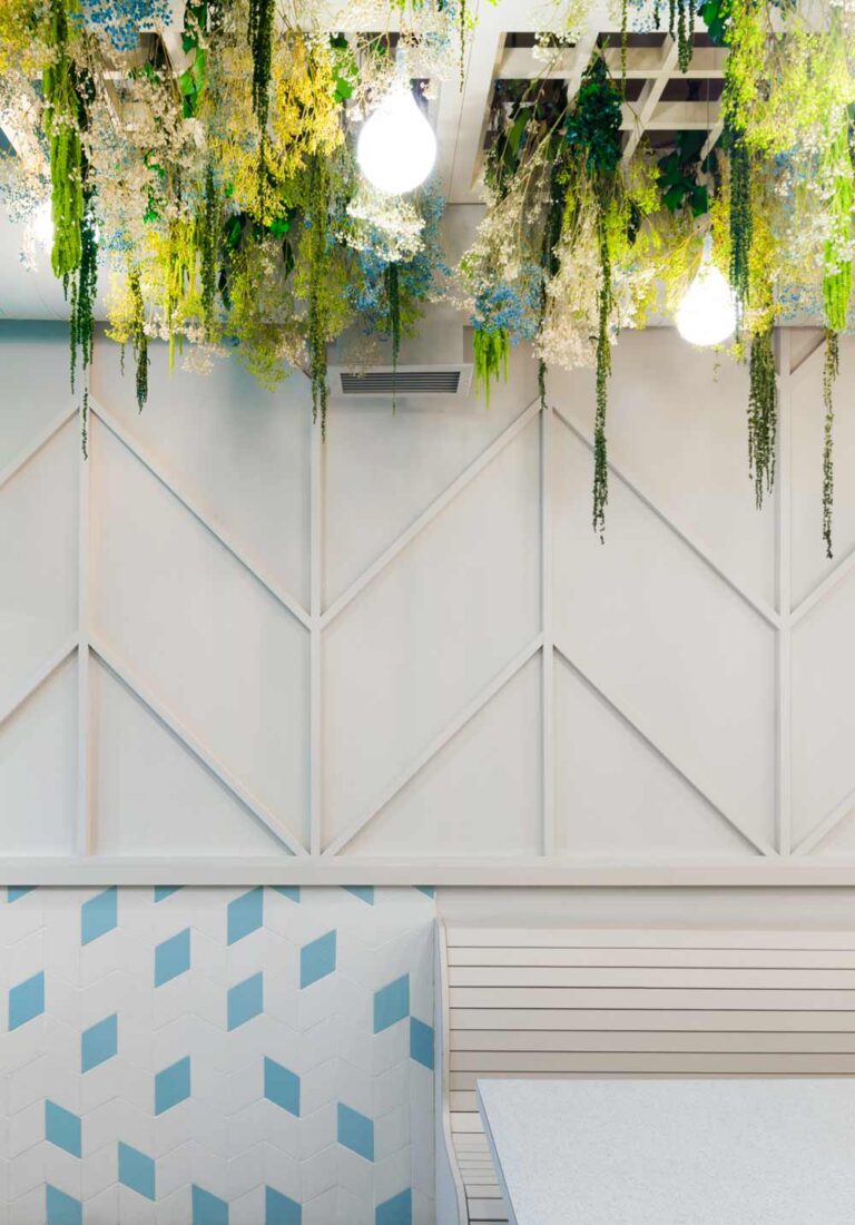 Vegetation hanging from the ceiling and chevron patterns that mimic the look of building rafters undulate throughout the restaurant and on the walls