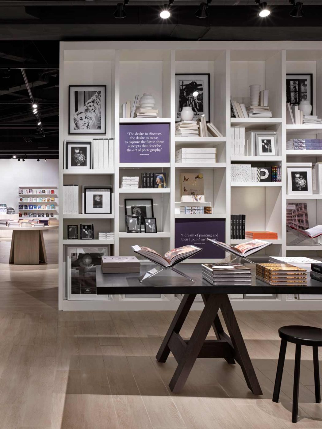 Residential look and feel-A vignette of a white book shelf with predominantly white items displayed on it, and some purple details, all resembling a built-in shelf in someone's home.