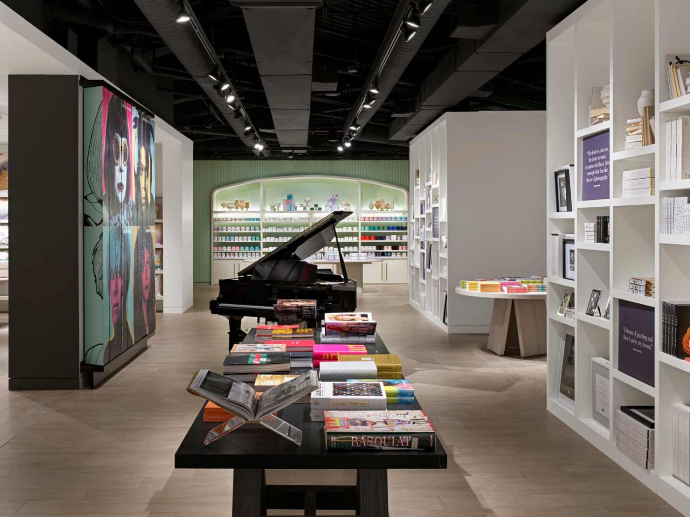 An area of the store featuring a large black piano, colorful books and products, and artwork on the walls