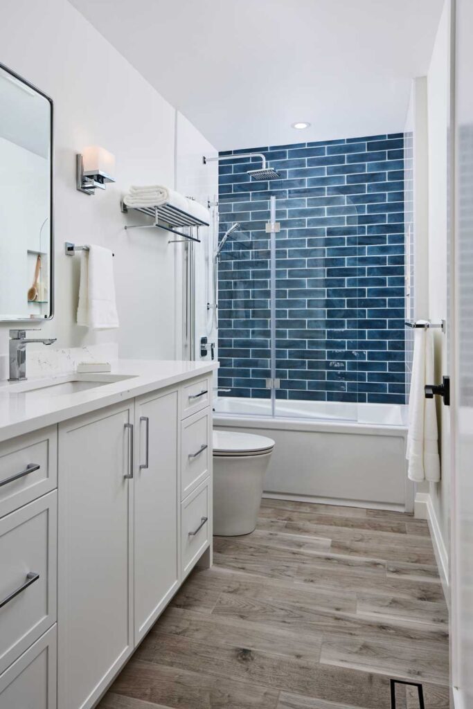 Guest bathroom in neutral color scheme with a blue accent wall in the shower