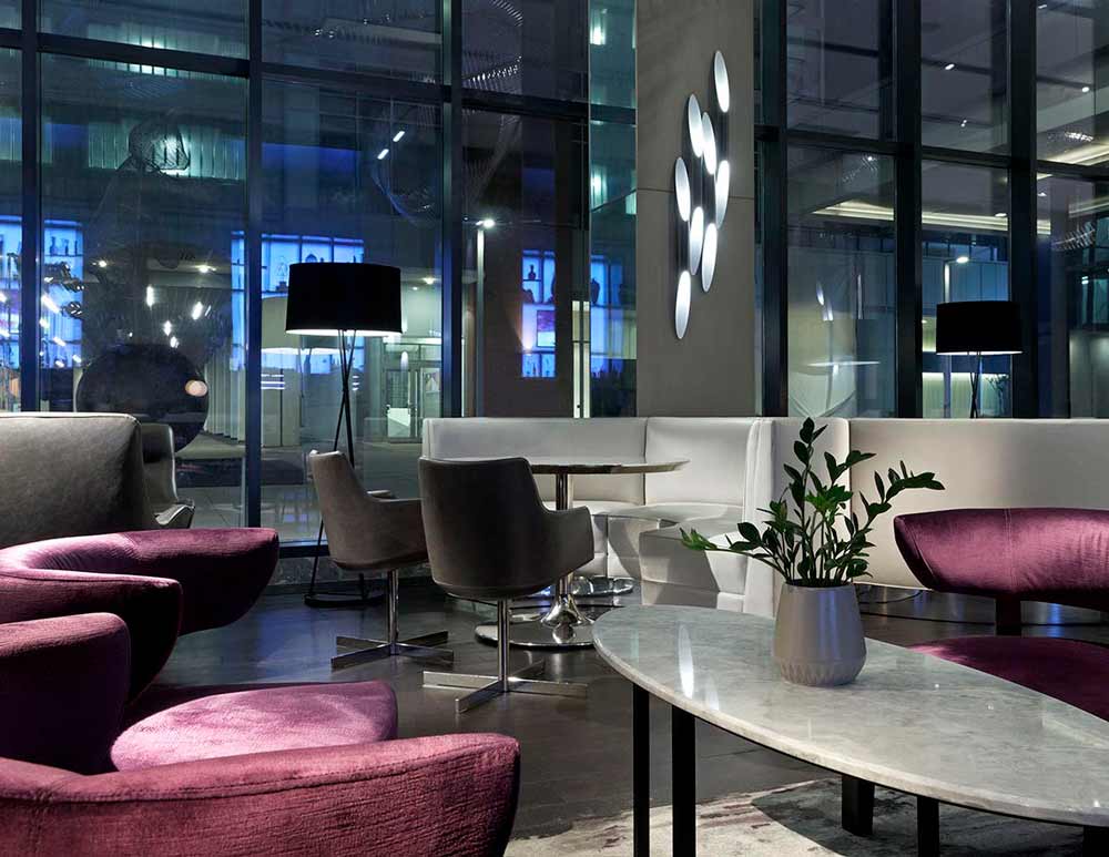 Lounge area in the lobby in predominantly neutral color scheme with some pink velvet chairs as accents