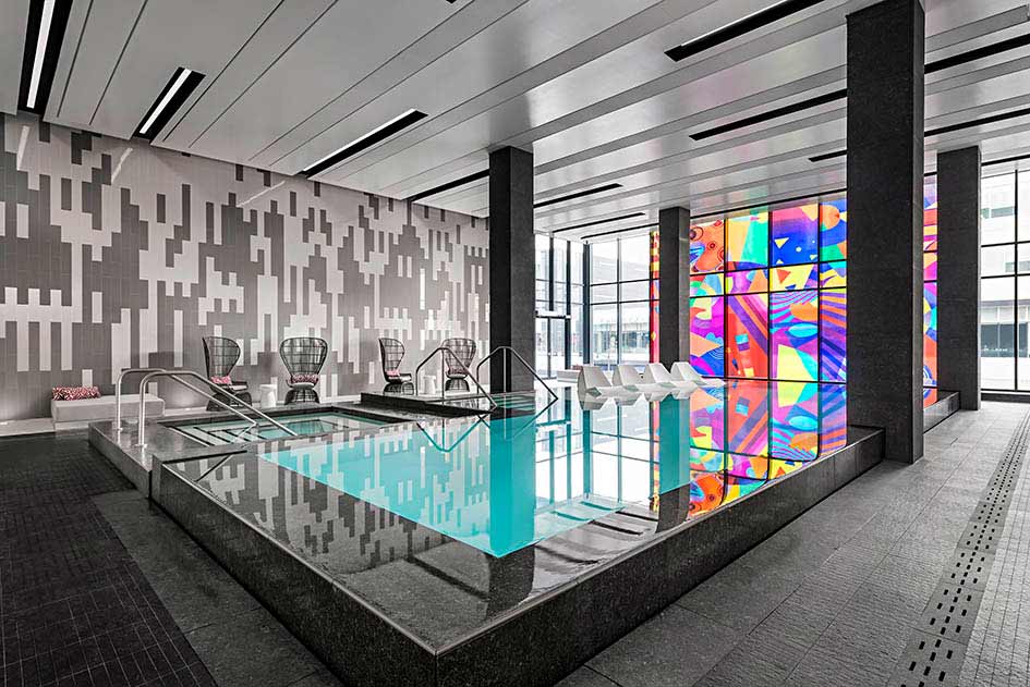 A view of the modern pool, with black and white tile wall in the back and contrasting colorfull glass feature wall on the other side