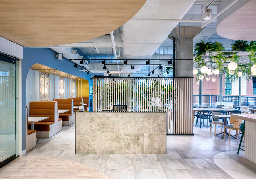 Reception desk with the cafeteria style boots and desk behind and biophilic design above