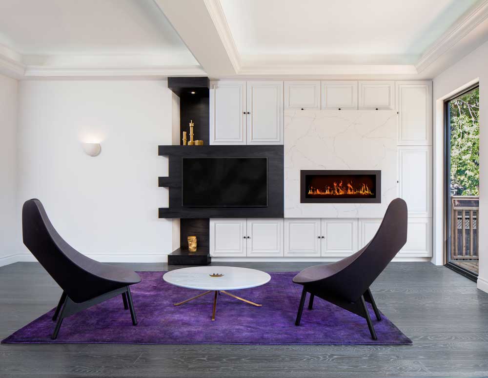 Living room with ample built in wall storage that incorporates a gas fire place as well as a large flat screen TV, modern black lounge chairs and purple accent area rug