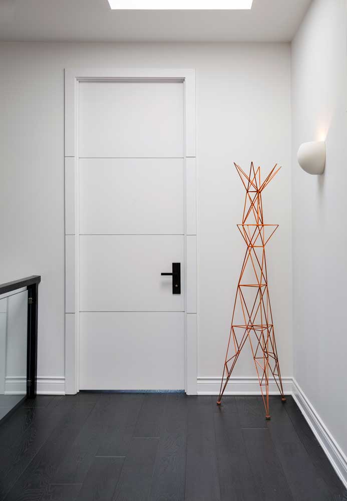 A white Hallway showcasing dark flooring and hardware, and gold coat hanger as an accent