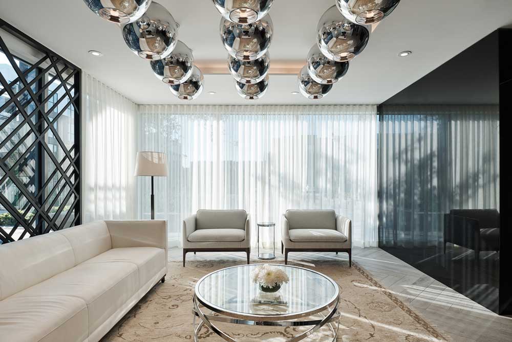 A bright living room setting with statement globe lighting above and neutral mid century furniture