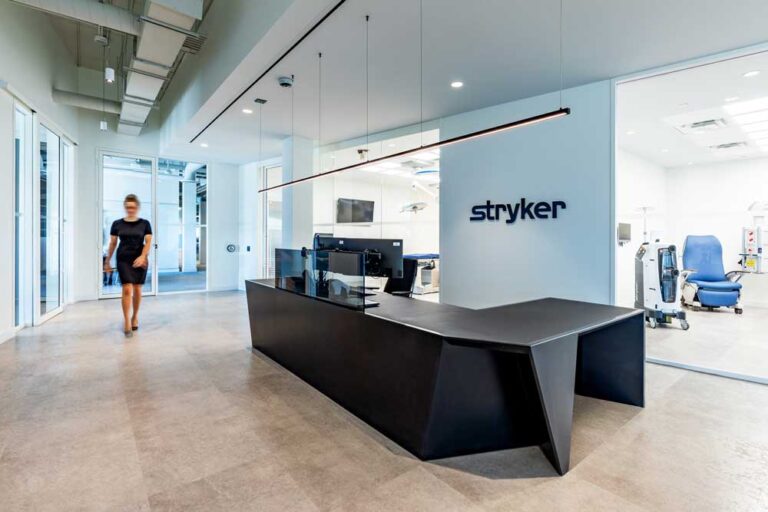 Stryker reception area and desk, in a black and white color scheme and an experience and learning center seen behind it through a glass wall