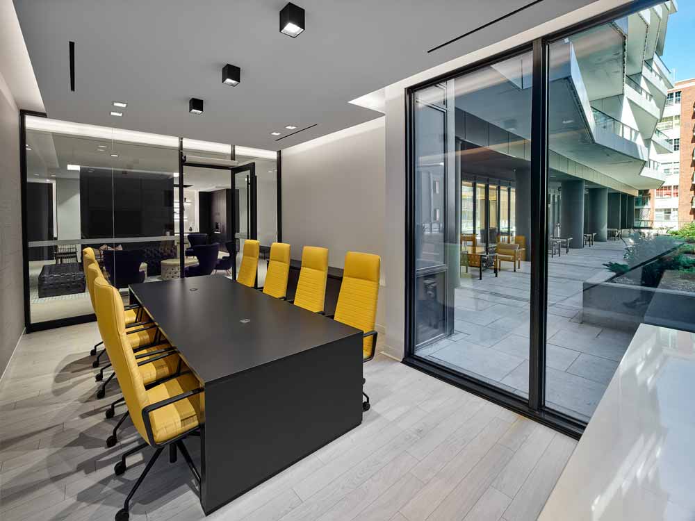 A conference room inside the party room area with the chairs as yellow accents against the whites, blacks and grays
