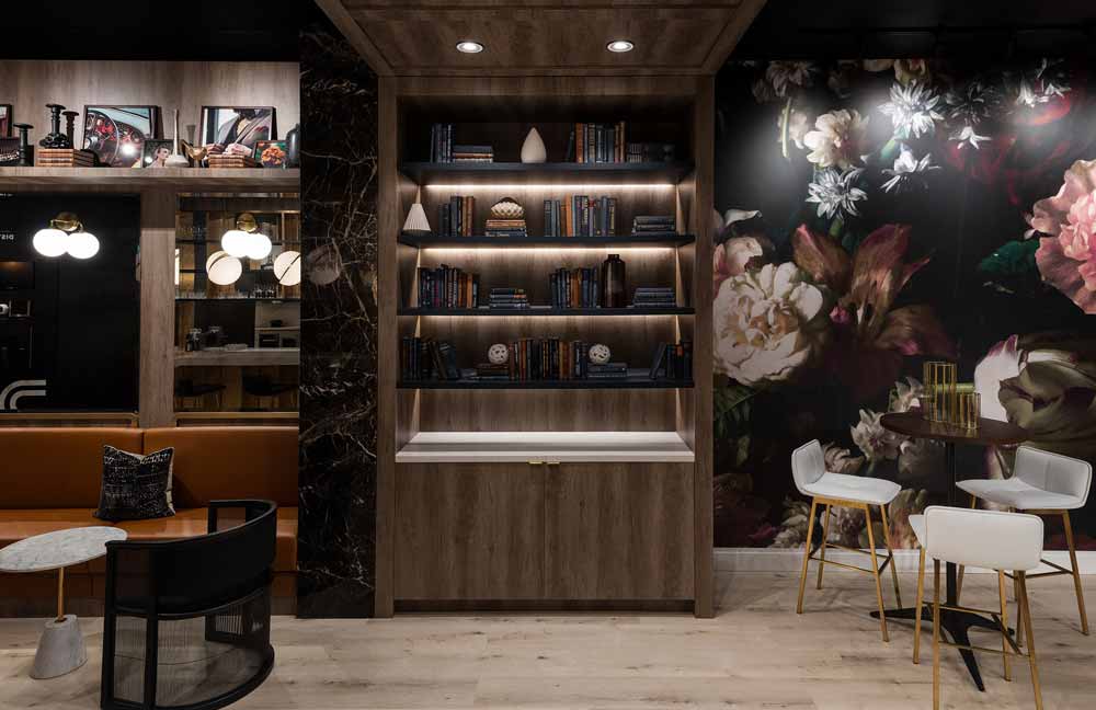 Luxurious yet relaxing atmoshphere is created with this large format floral wall paper in dark tones along with the wooden built in library and mood lighting