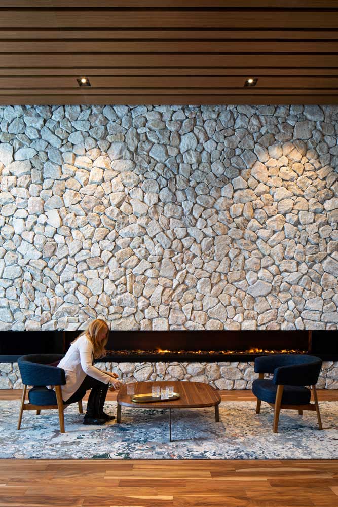 A view of the party room lounge area with mid century style seating with the stone wall as the backdrop and beautiful wooden slat ceiling above