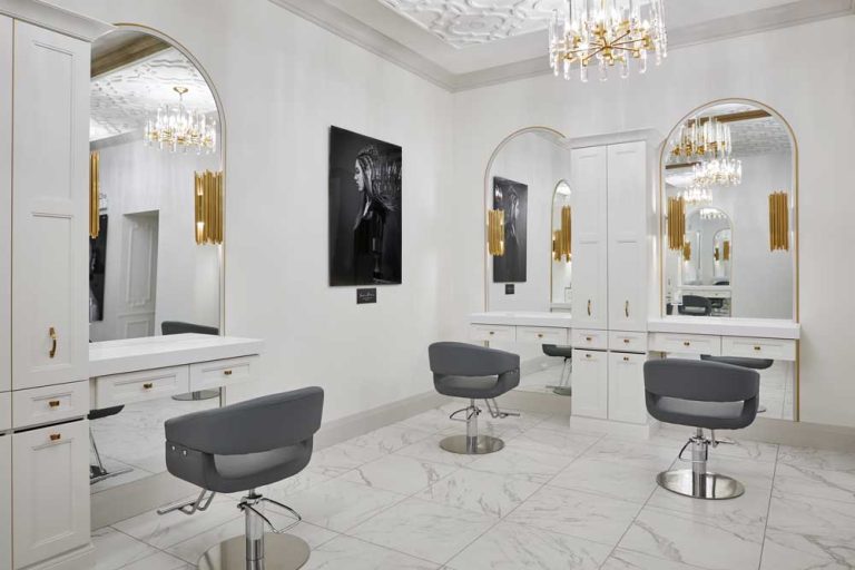 Spacious hair styling studio in predominantly white and gold colour scheme, built in cabinetry beside mirrors
