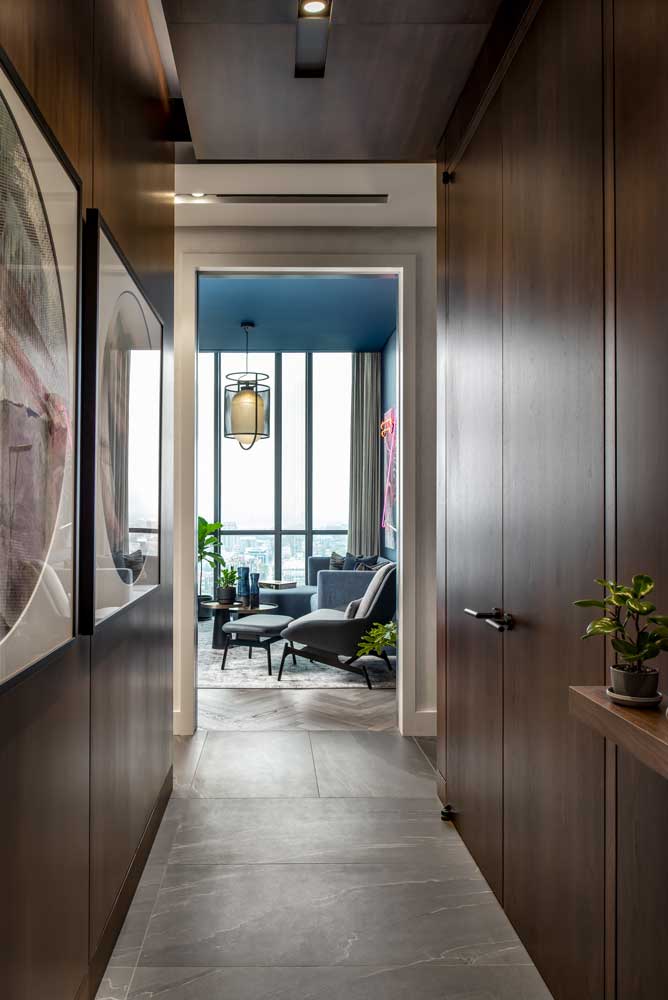 Narrow hallway with wood panelling on all sides leading to the living area