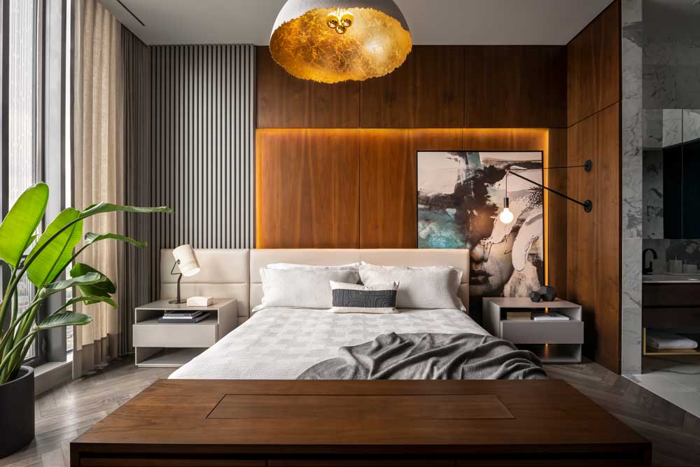 Main bedroom featuring wood panelling that frames the bed and features large statement art piece