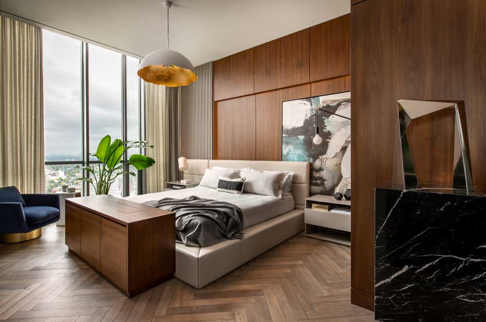 Main bedroom featuring wood panelling that frames the bed and features large statement art piece
