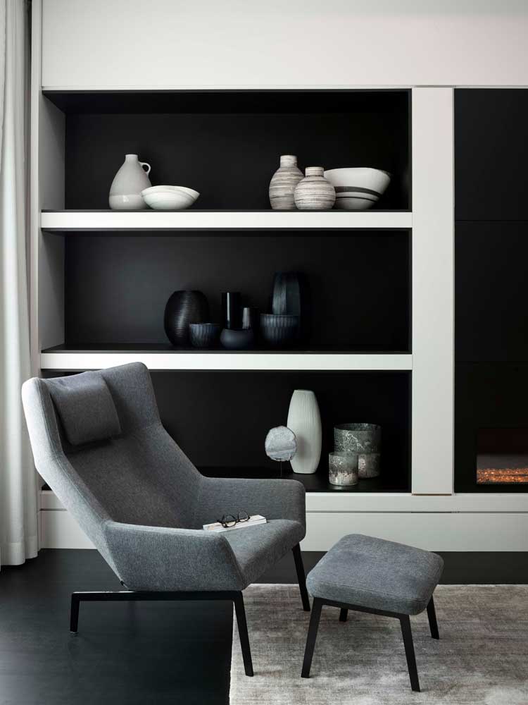 Contemporary gray chair with white built in shelving against black background behind