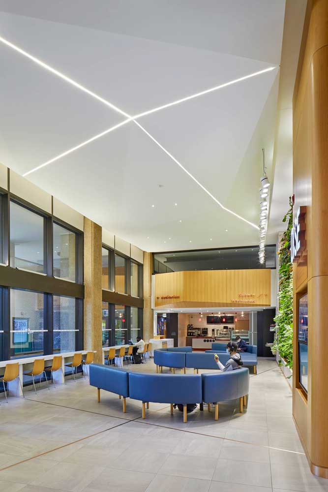 View of the lobby with modular curvy seating in a blue colour and seating area along the wall of windows