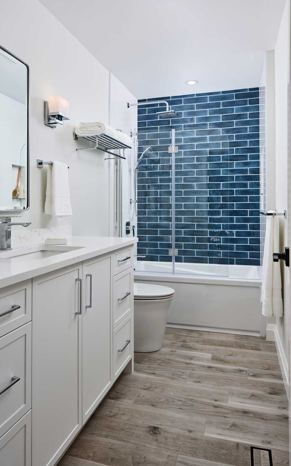 Modern guest bathroom with stunning blue wall tile in the bathtub area and clean white vanity